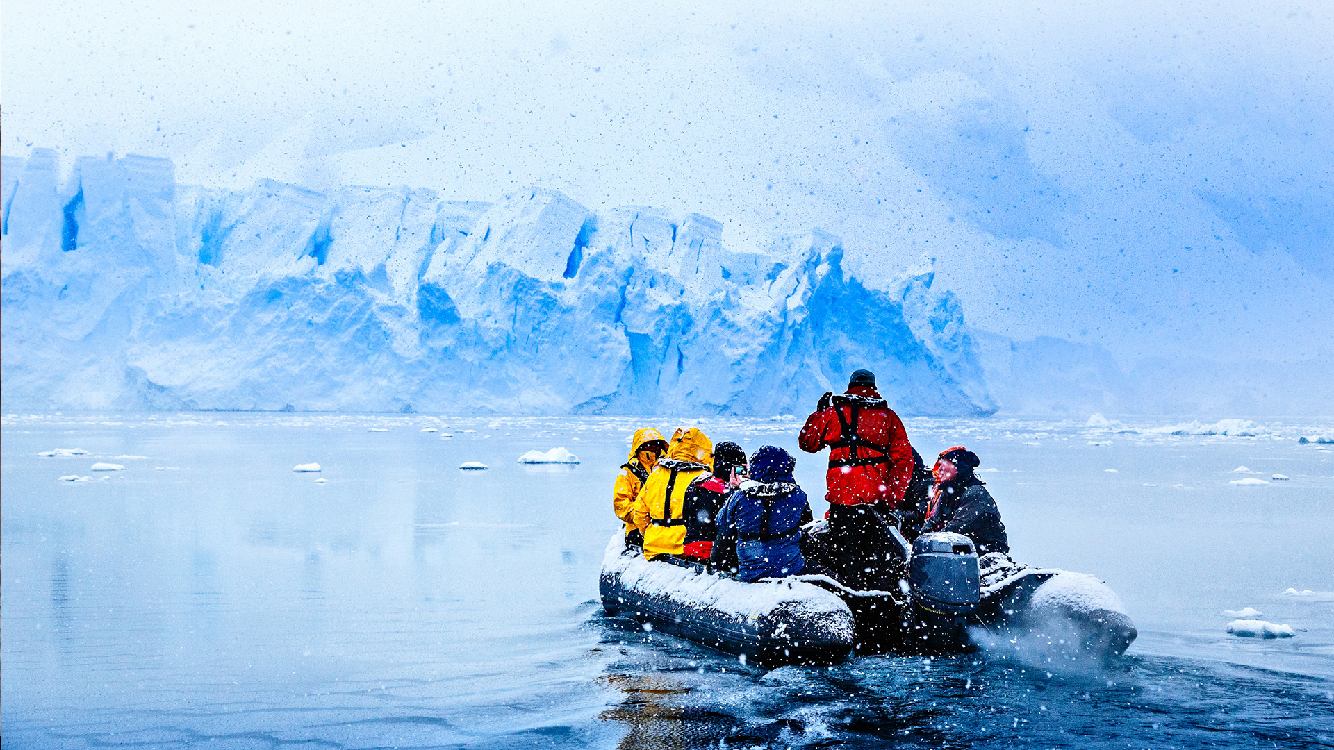 Passengers in a zodiac during snowfall