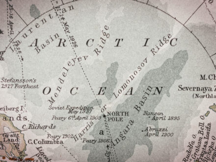 An antique map shows the Arctic Ocean centered around the North Pole, with labeled basins, ridges, and historical exploration routes.